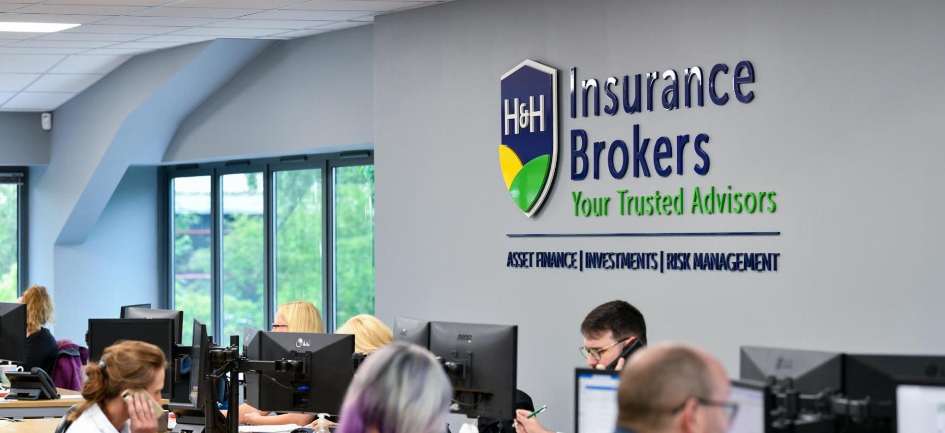 Image of inside H&H Insurance Carlisle offices looking at a large sign onn the wall