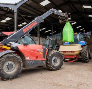 fork lift lifting a bag of feed on a farm